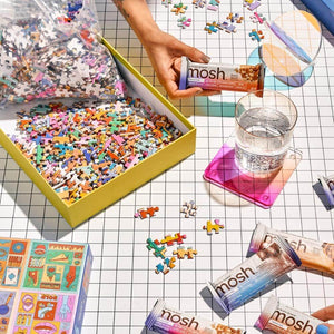 MOSH bar wrapper and glass of water next to a colorful jigsaw puzzle box